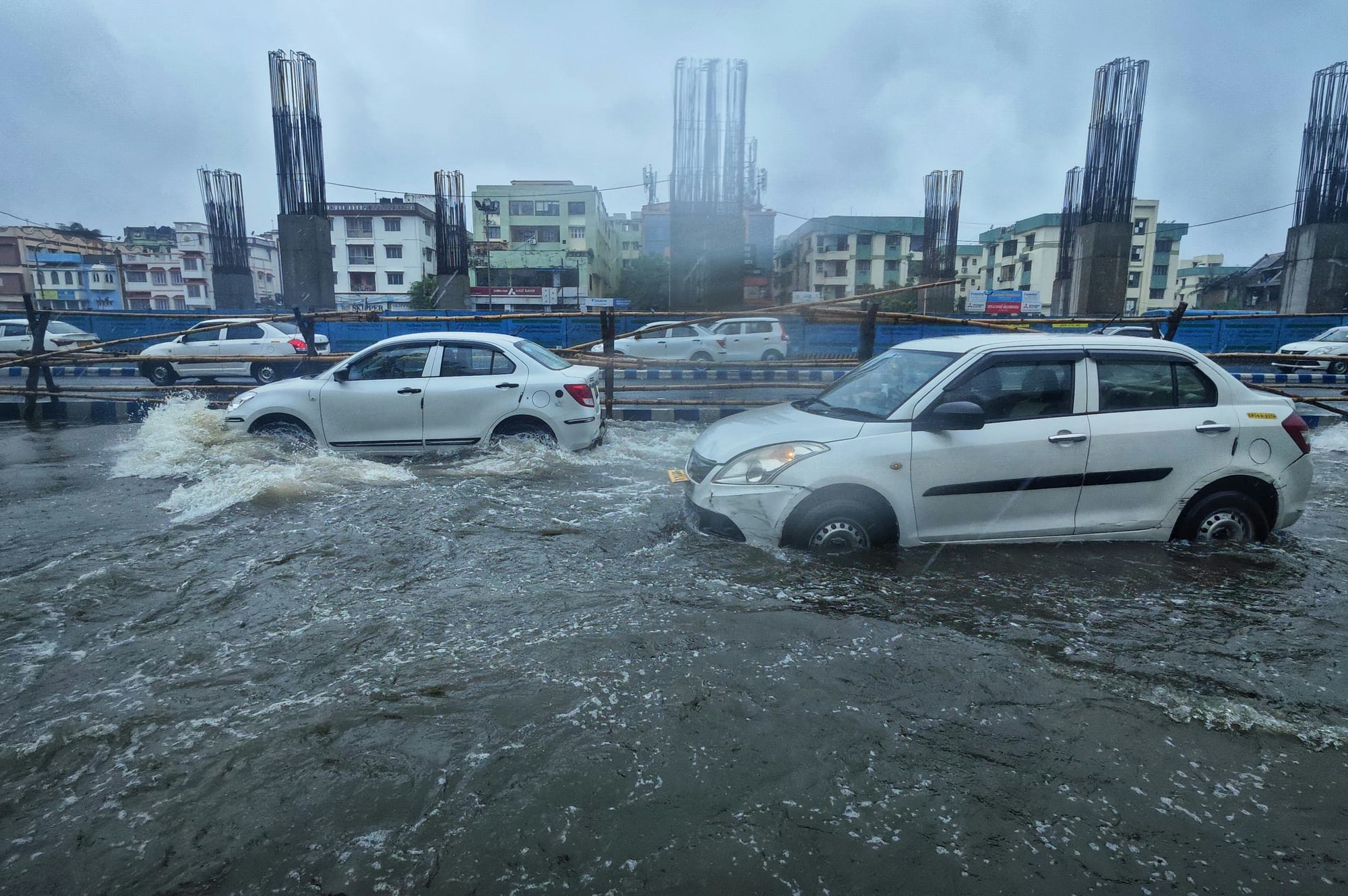Cars driving through a city road that's flooded by stormwater.